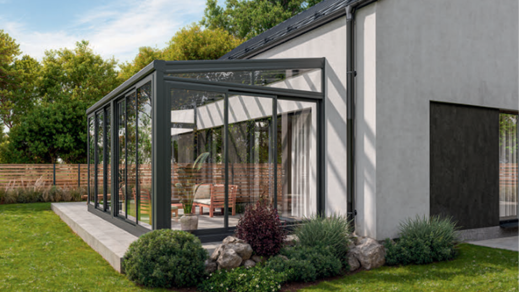 Przestronny ogród zimowy z aluminiową konstrukcją i panoramicznymi przeszkleniami przy domu jednorodzinnym. Oferta dla klientów z Międzyrzecza i okolic